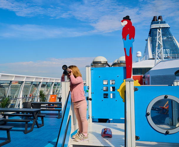 Flicka kollar ut genom kikare på ett kryssningsfartyg